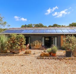 An outdoor view of a building with solar panels and plants at The Dairy in Bridport