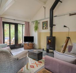 A living room with a wood stove and television at The Dairy in Bridport