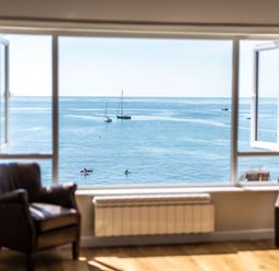 A room with two chairs facing a window overlooking the sea with boats at 3 Beach Way House Lyme Regis