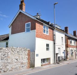A row of houses with a stone wall and a street lamp on a street at Bay View in Lyme Regis