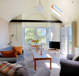 A living room with sofas a coffee table dining table and TV at Bay View in Lyme Regis