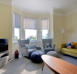 A living room with two armchairs a green sofa a wooden coffee table and a television at 7 Seafield Road in Seaton