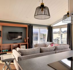 A living room with couches facing a mounted TV and large windows with curtains at Hazelwood 4 Pinewood Retreat in Pinewood