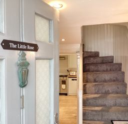 An open door with a sign The Little Rose showing a carpeted staircase and a kitchen in the background at The Little Rose in Lyme Regis