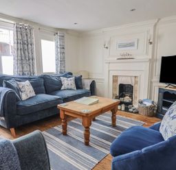 A living room with a sofa and television at The Little Rose in Lyme Regis