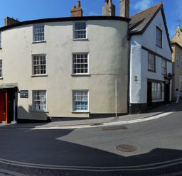 A street view with old buildings and a shop with red framing at Driftwood in Lyme Regis