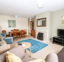A living room with sofas a wooden dining table a TV on a stand and a fireplace at Sunny Haven in Preston