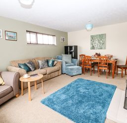 A living room with sofas a blue rug a dining table with chairs and a fireplace at Sunny Haven in Preston