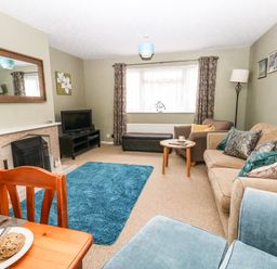 A living room with sofas a television on a stand and a blue rug at Sunny Haven in Preston