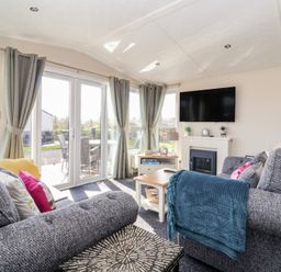 A living room with a television and a sliding door at Away Daze in Carnaby near Bridlington
