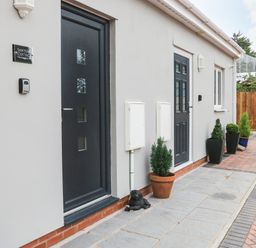 A view of two black doors on a white wall with potted plants on the ground at Sawtons Cottage 2 in Dawlish