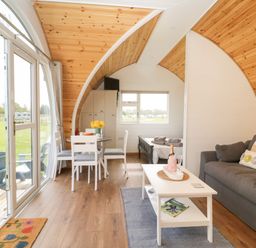An open plan living area with a sofa coffee table dining table and a bed visible at Poppy Seaton near Hornsea