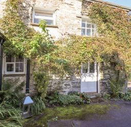 A stone cottage exterior with ivy growing around windows and door at Yanway Cottage in Troutbeck near Troutbeck Bridge