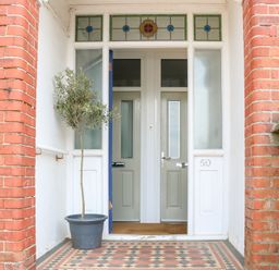 An entrance with a tiled floor a potted plant and two doors with stained glass windows above at Flat 1 Hunstanton