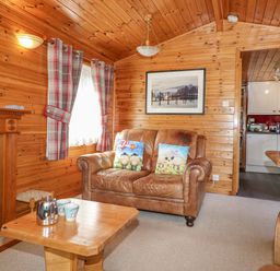A living room with leather sofa and wooden coffee table near a fireplace at Robins Nest Number 12 Burnside Park near Keswick