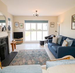 A living room with a blue sofa a fireplace and a rug at Stillwaters in Bushmills County Antrim
