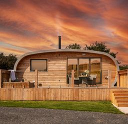 A wooden pod with a deck table and chairs and hot tub in front at Low Longlands in Cartmel
