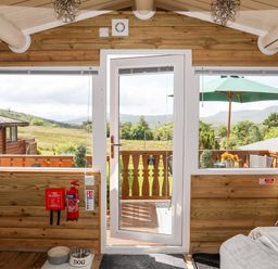 A wooden room with a glass door leading to a balcony and outdoor umbrella at Ty Coed - 63 in Bronaber near Trawsfynydd