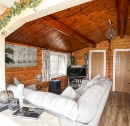 A living room with a grey sofa a television wooden walls and ceiling at Ty Coed - 63 in Bronaber near Trawsfynydd