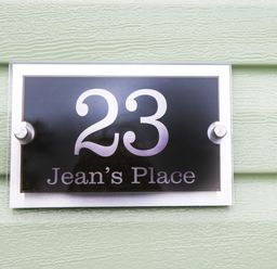 A house number sign 23 Jean's Place on a green textured wall at Jean's Place in East Heslerton near West Heslerton