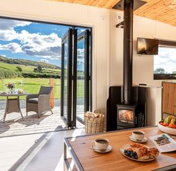 A kitchen with coffee and pastries on a table a wood stove and outdoor seating at Little Heaning in Cartmel