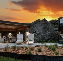 An outdoor garden with deck chairs and a stone wall at Little Heaning in Cartmel