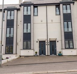 A row of modern townhouses with multiple floors and large windows at 6 Ocean Heights in Newquay
