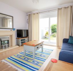 A living room with a fireplace television coffee table sofa and sliding glass door at 6 Ocean Heights in Newquay