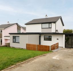 A two story house with a driveway and a wooden fence at Daresfield in Cemaes Bay