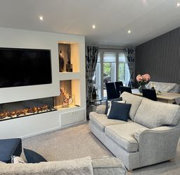 A living room with a fireplace and dining table at Loluke Lodge on The Lake 5 Coniston Drive, Borwick near Carnforth