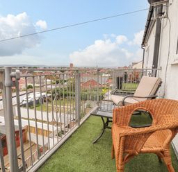 A balcony with artificial grass and two chairs overlooking rooftops at Ty Uchaf in Rhyl