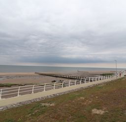 A beach with a walkway and white railing near the sea at Ty Uchaf in Rhyl