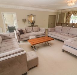 A living room with three sofas a wooden coffee table and a dining table with chairs at Bodmin Country House in Lanivet