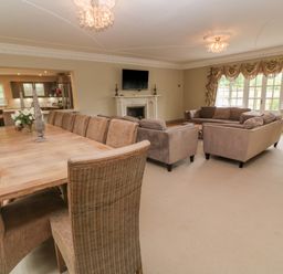 A living room with sofas a fireplace and a dining table with chairs at Bodmin Country House in Lanivet