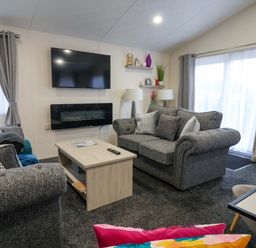 A living room with a sofa and television at Brighter Daze in Carnaby near Bridlington
