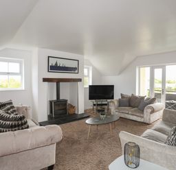A living room with sofas coffee table television and wood burner at The Old Coal Yard in Cemaes Bay