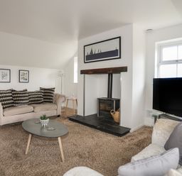 A living room with sofas a coffee table a fireplace and a television at The Old Coal Yard in Cemaes Bay