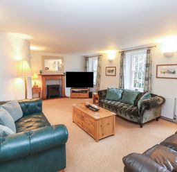 A living room with sofas, a coffee table, a television, and a fireplace at Huntingstile Lodge in Grasmere