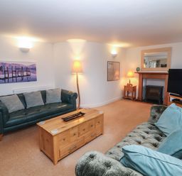 A living room with two sofas a wooden coffee table a television and lamps at Huntingstile Lodge in Grasmere