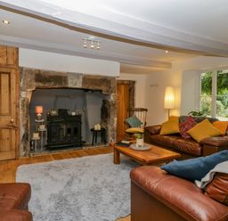 A living room with leather sofas and a wooden coffee table near a fireplace at Pentre Court Cottage in Abergavenny