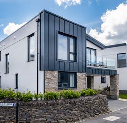 A modern residential building with stone and metal facade at Chapel Rock Close