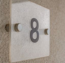 A glass plaque with the number 8 mounted on a textured wall at Beach Haven in Perranporth