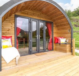 A wooden pod structure with glass doors and red curtains on a wooden deck at Hartsop Magic - Crossgate Luxury Glamping in Hartsop near Glenridding