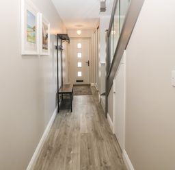 A hallway with a wooden bench coat rack framed pictures and staircase at 1 Crud Y Mor in Barmouth