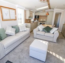 A living room with two sofas and an ottoman next to a kitchen area at Vendee Lodge Thorness Bay Holiday Park near Cowes