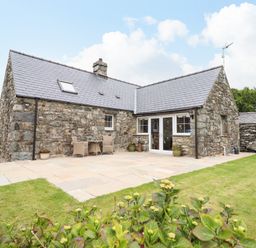 A stone cottage with a tiled roof patio area and garden at Caerffynon Bach in Dyffryn Ardudwy