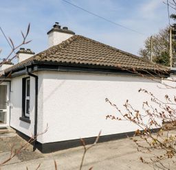 Exterior of a white house with a tiled roof and a glass door at Bridgetown Cottage in Kerrykeel County Donegal