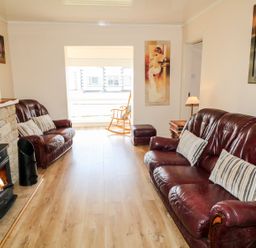 A living room with two leather sofas a wood burning stove and a rocking chair at Bridgetown Cottage in Kerrykeel County Donegal