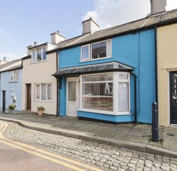 A row of terraced houses with different colored facades along a paved street at Penrallt in Cemaes Bay