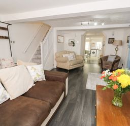 A living room with sofas, a wooden coffee table with flowers, and a blue fireplace at Penrallt in Cemaes Bay